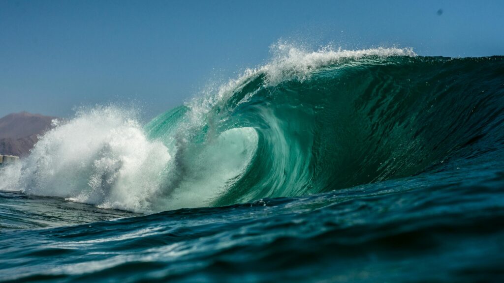 A crashing wave transitioning from dark blue, to turquoise, to a white frothy crest.