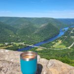 Coffee in a blue mug sitting on the rim of the overlook of the West Branch Susquehanna River